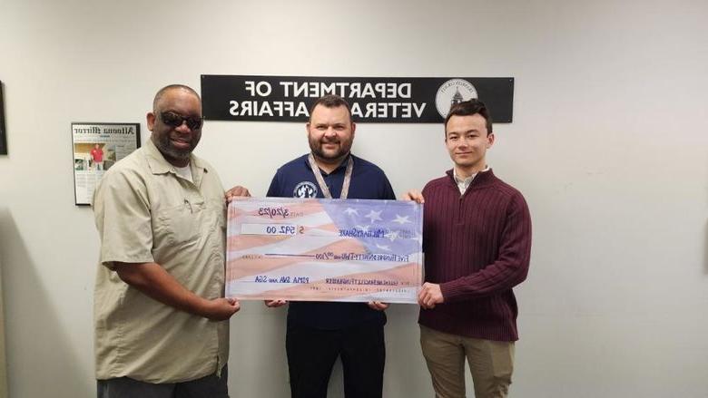 学生 hold a check written out to MilitaryShare Program